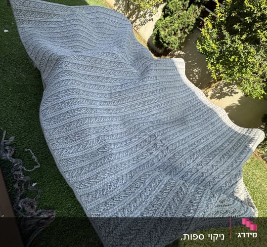 שטיח אפור נקי פרוש להתייבשות בשמש בחצר הבית לאחר ניקוי